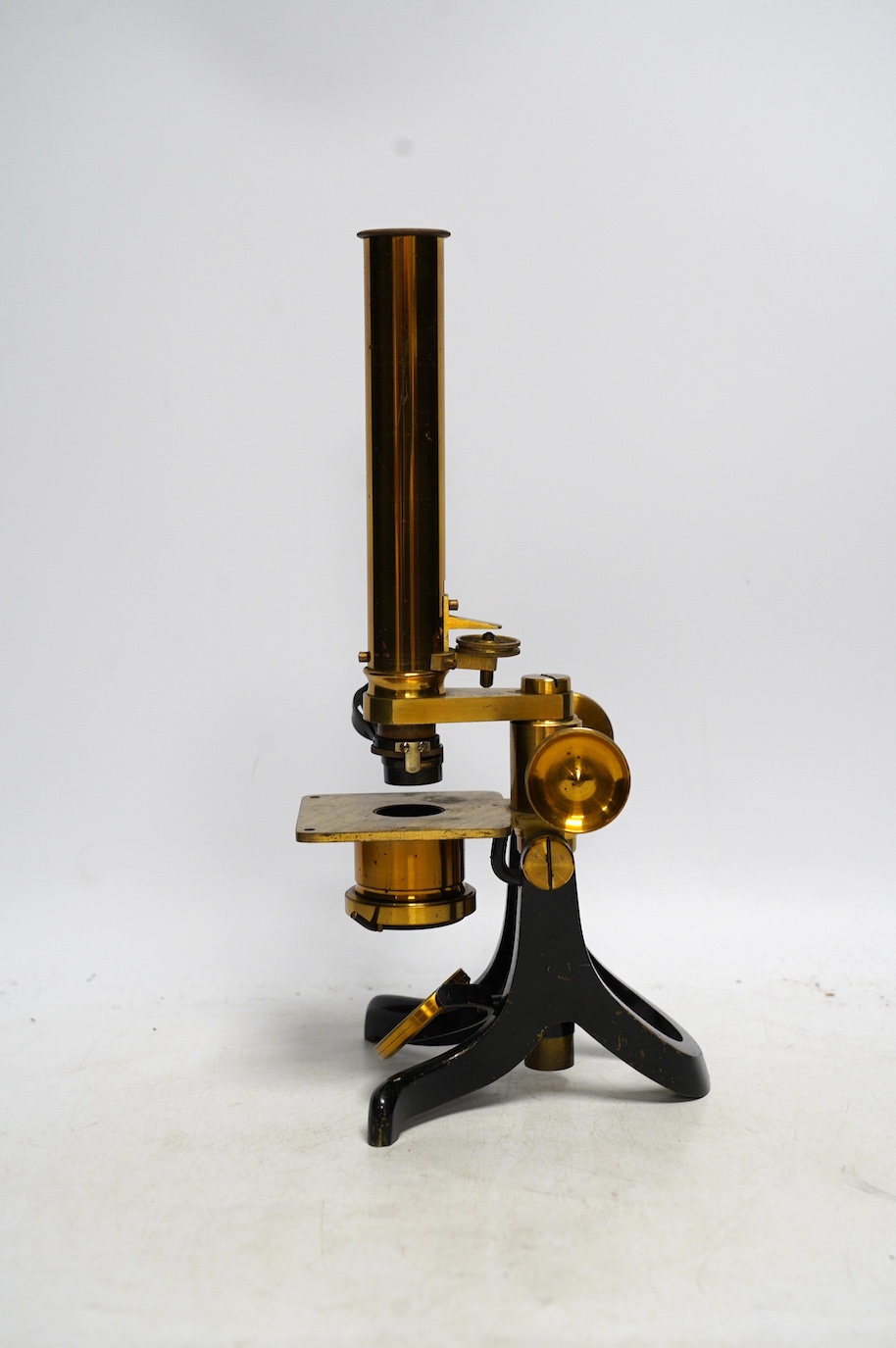 An unmarked late 19th century monocular brass microscope, in a fitted mahogany case with alternative lenses, a drawer for slides and other accessories, case 39cm high. Condition - fair to good